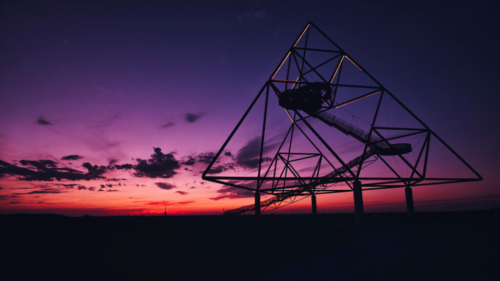 Der beleuchtete Tetraeder in Bottrop vor violett-rotem Abendhimmel