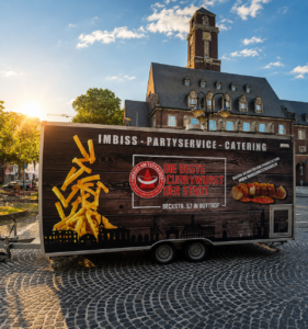 Foodtruck des Imbiss am Tetraeder vor einem Rathaus im Abendlicht